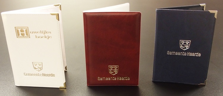 Overzicht trouwboekjes. Van links naar rechts: wit lederen boekje, rood kunstof boekje, blauw lederenboekje
